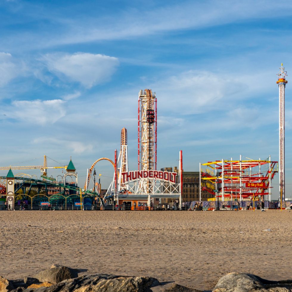 This is a color photograph of a theme park roller coaster on a beach.